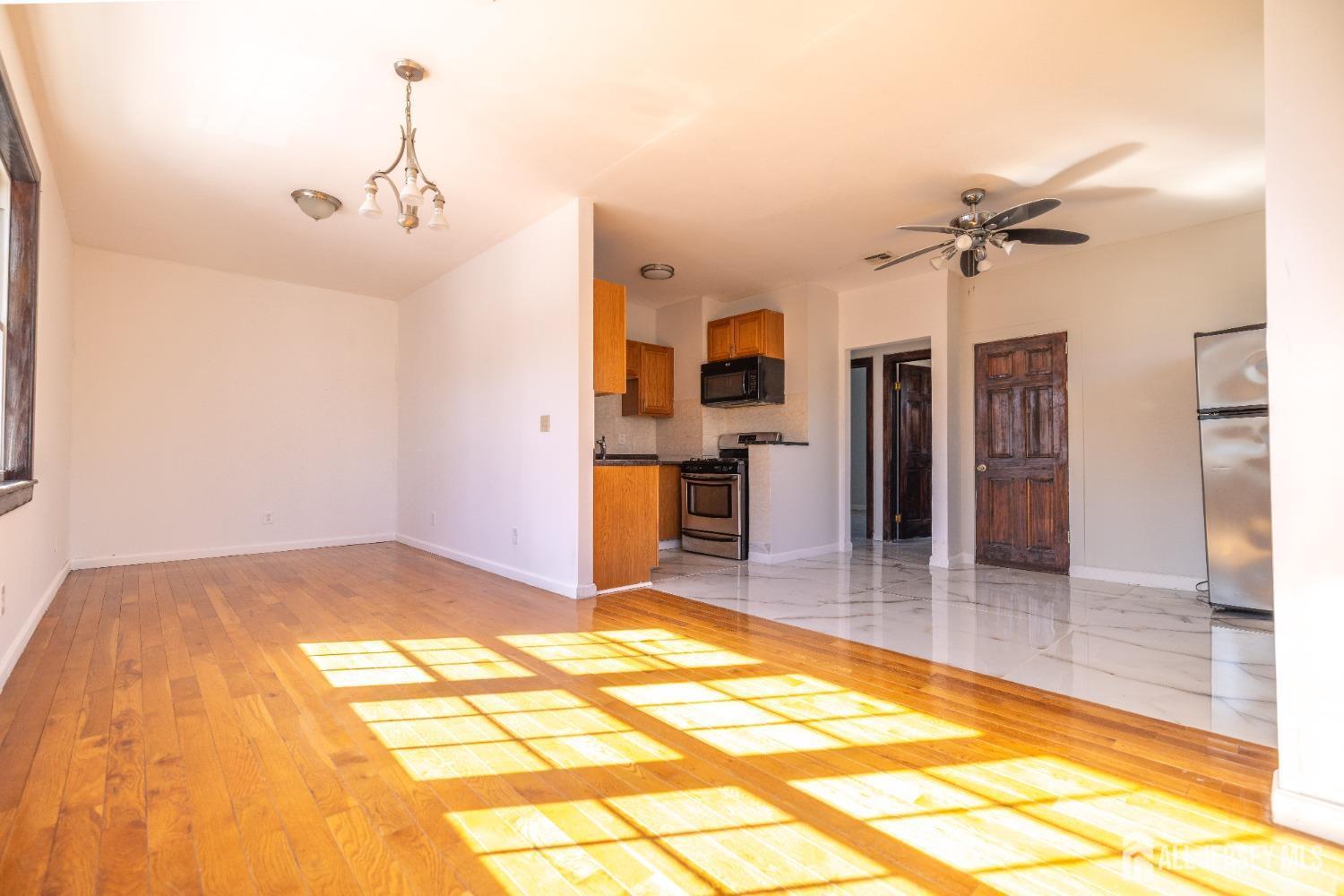 a view of a livingroom with a chandelier fan and kitchen view