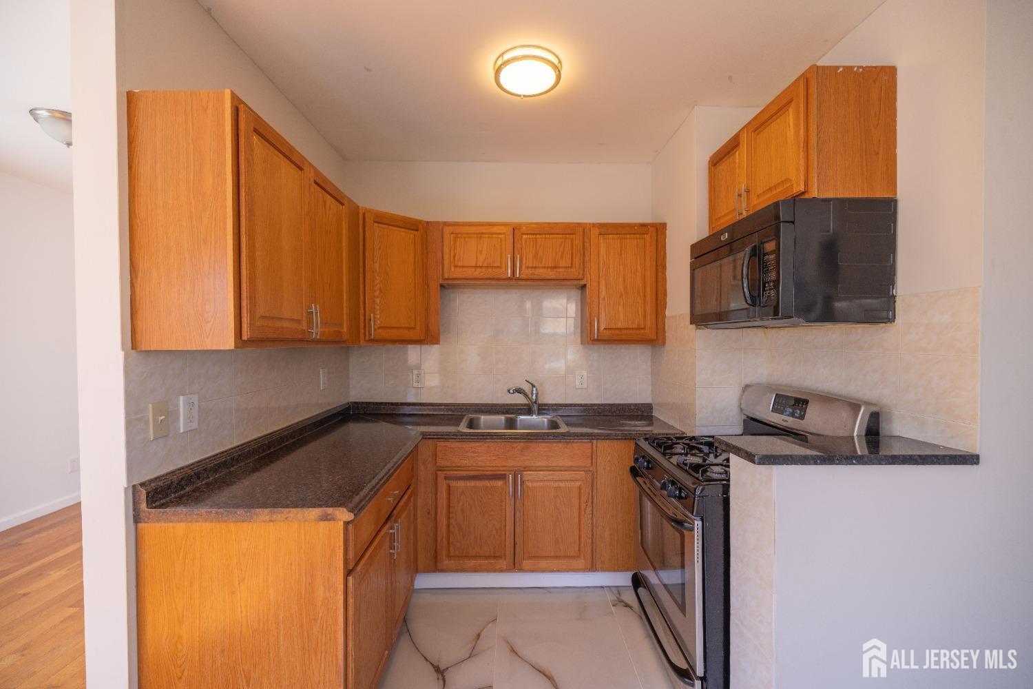 60 Sampson Street Garfield, NJ 07026 - Photo 5 of 9 a kitchen with stainless steel appliances granite countertop a sink stove and microwave