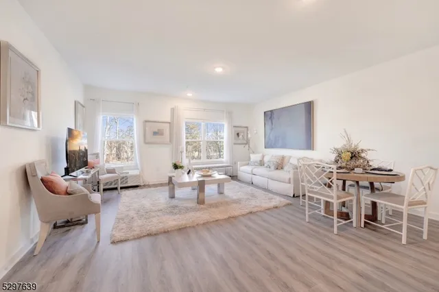 a living room with furniture a wooden floor and next to a window