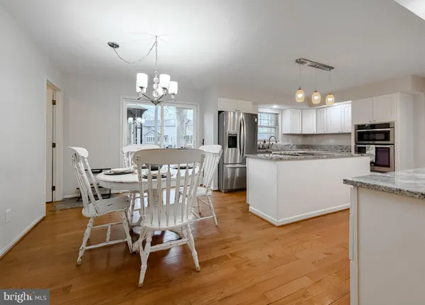 a kitchen with stainless steel appliances a sink a stove a refrigerator cabinets and dining table