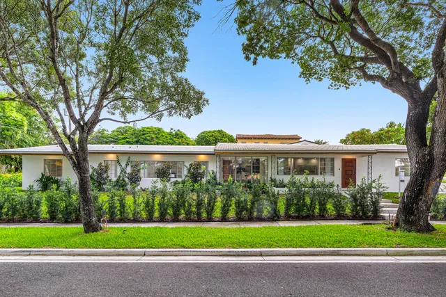 a front view of a house with a garden and trees