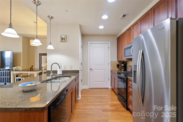 a kitchen with stainless steel appliances granite countertop a sink refrigerator and cabinets