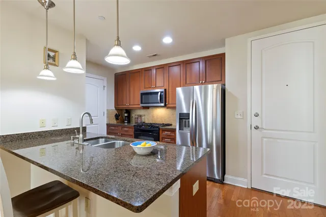 a kitchen with stainless steel appliances granite countertop a sink a refrigerator and a granite counter tops