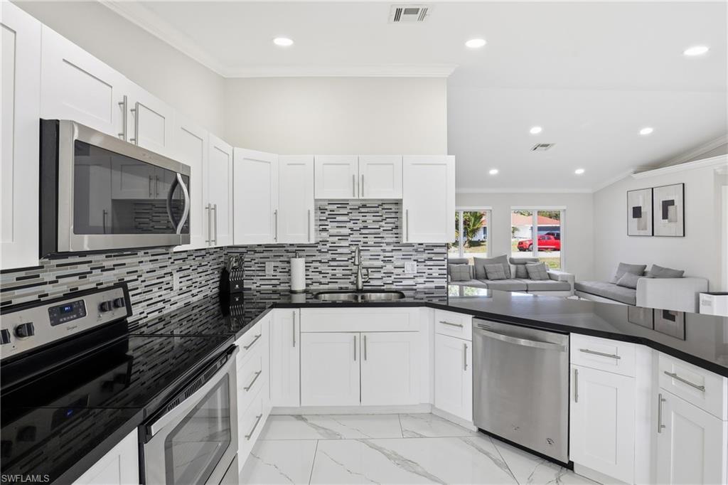 5312 17th Avenue Southwest Naples, FL 34116 - Photo 44 of 45 Kitchen with ornamental molding, stainless steel appliances, open floor plan, recessed lighting, and light marble finish floors
