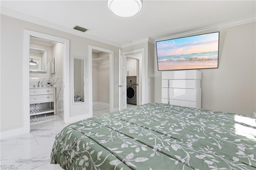 5312 17th Avenue Southwest Naples, FL 34116 - Photo 18 of 45 Bedroom with ornamental molding, light marble finish flooring, a spacious closet, connected bathroom, and washer / dryer