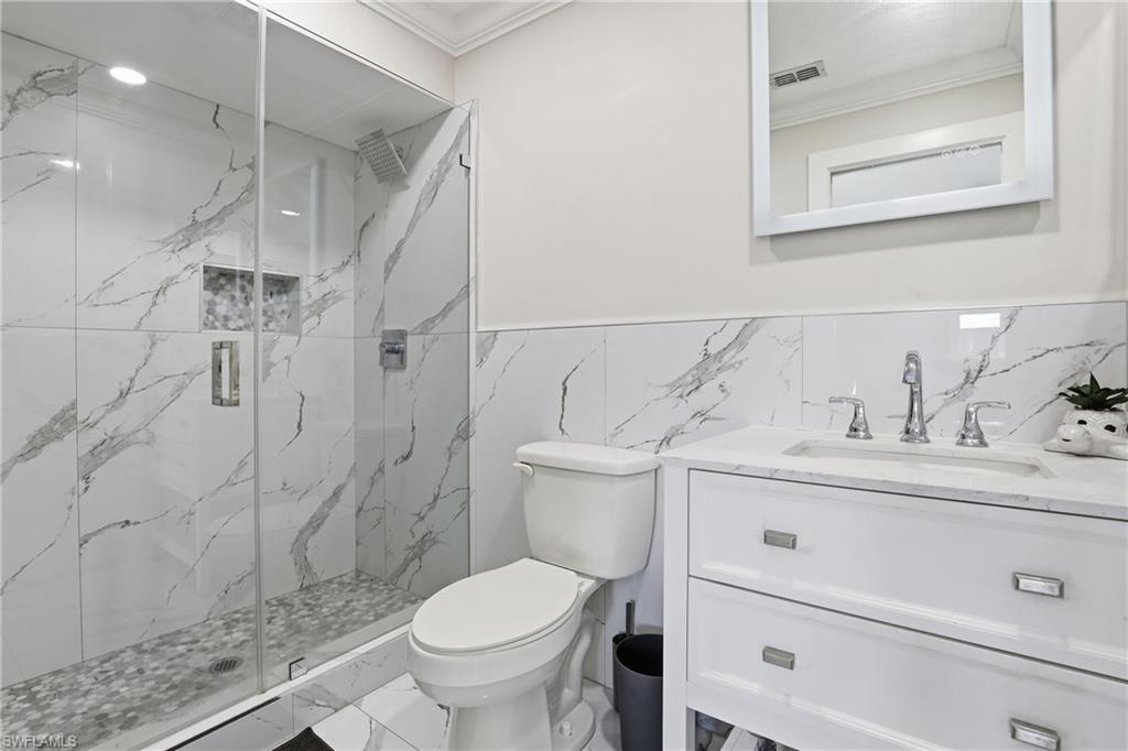 5312 17th Avenue Southwest Naples, FL 34116 - Photo 19 of 45 Full bathroom featuring vanity, a marble finish shower, crown molding, marble look tile flooring, and tile walls