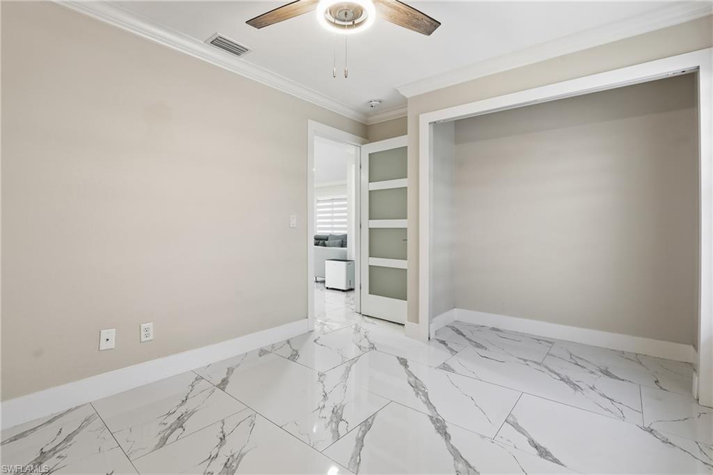 5312 17th Avenue Southwest Naples, FL 34116 - Photo 24 of 45 Unfurnished room with built in shelves, ornamental molding, light marble finish floors, and a ceiling fan