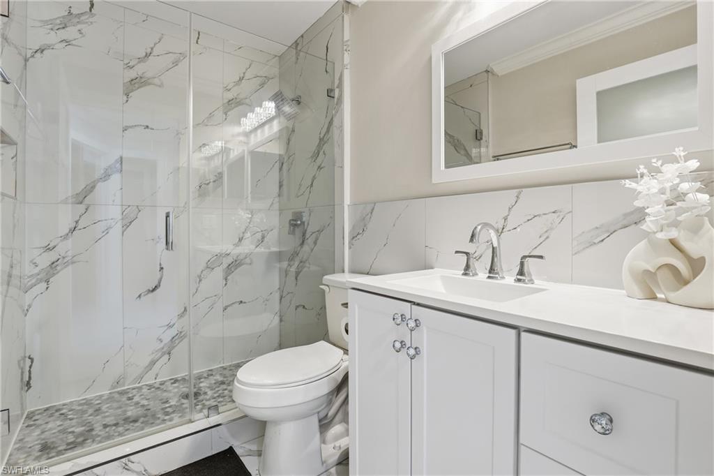 5312 17th Avenue Southwest Naples, FL 34116 - Photo 25 of 45 Full bathroom featuring vanity, a marble finish shower, marble finish flooring, and tile walls