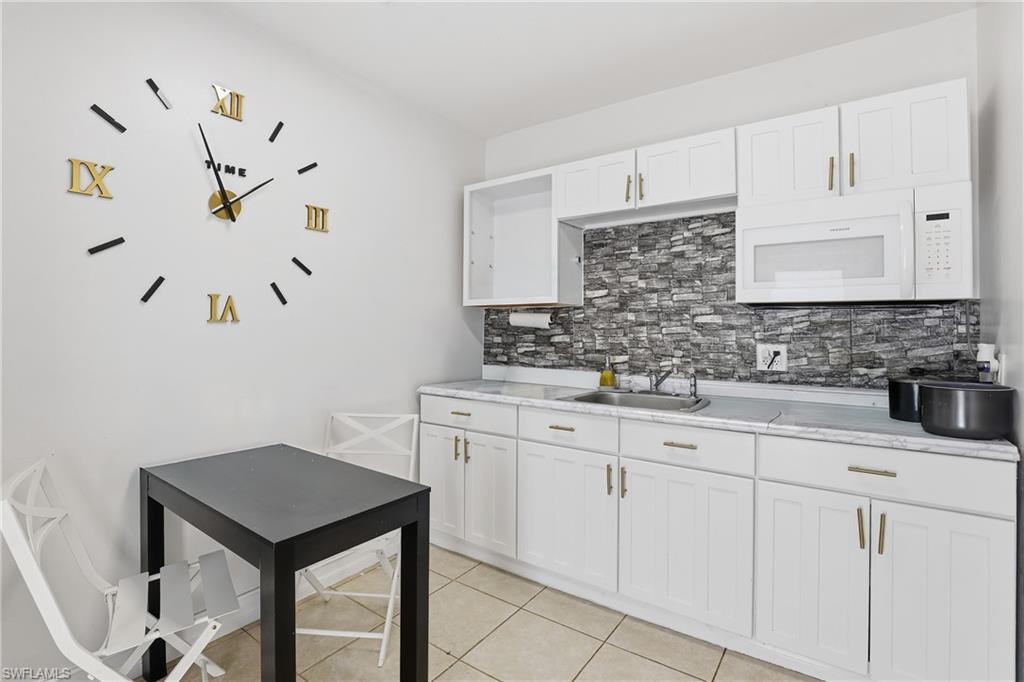 5312 17th Avenue Southwest Naples, FL 34116 - Photo 27 of 45 Kitchen featuring white microwave, light countertops, white cabinets, and light tile patterned floors