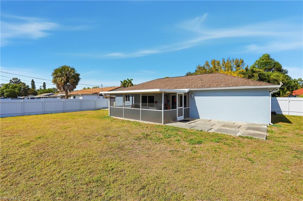 5312 17th Avenue Southwest Naples, FL 34116 - Photo 36 of 45 Rear view of house with a sunroom, a fenced backyard, stucco siding, and roof with shingles