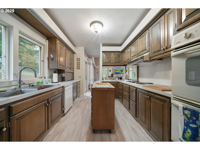 a kitchen with kitchen island granite countertop a sink cabinets and stainless steel appliances