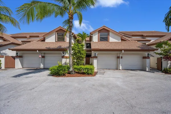 a view of a house with a yard and palm trees
