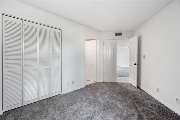 an empty room with closet and a ceiling fan