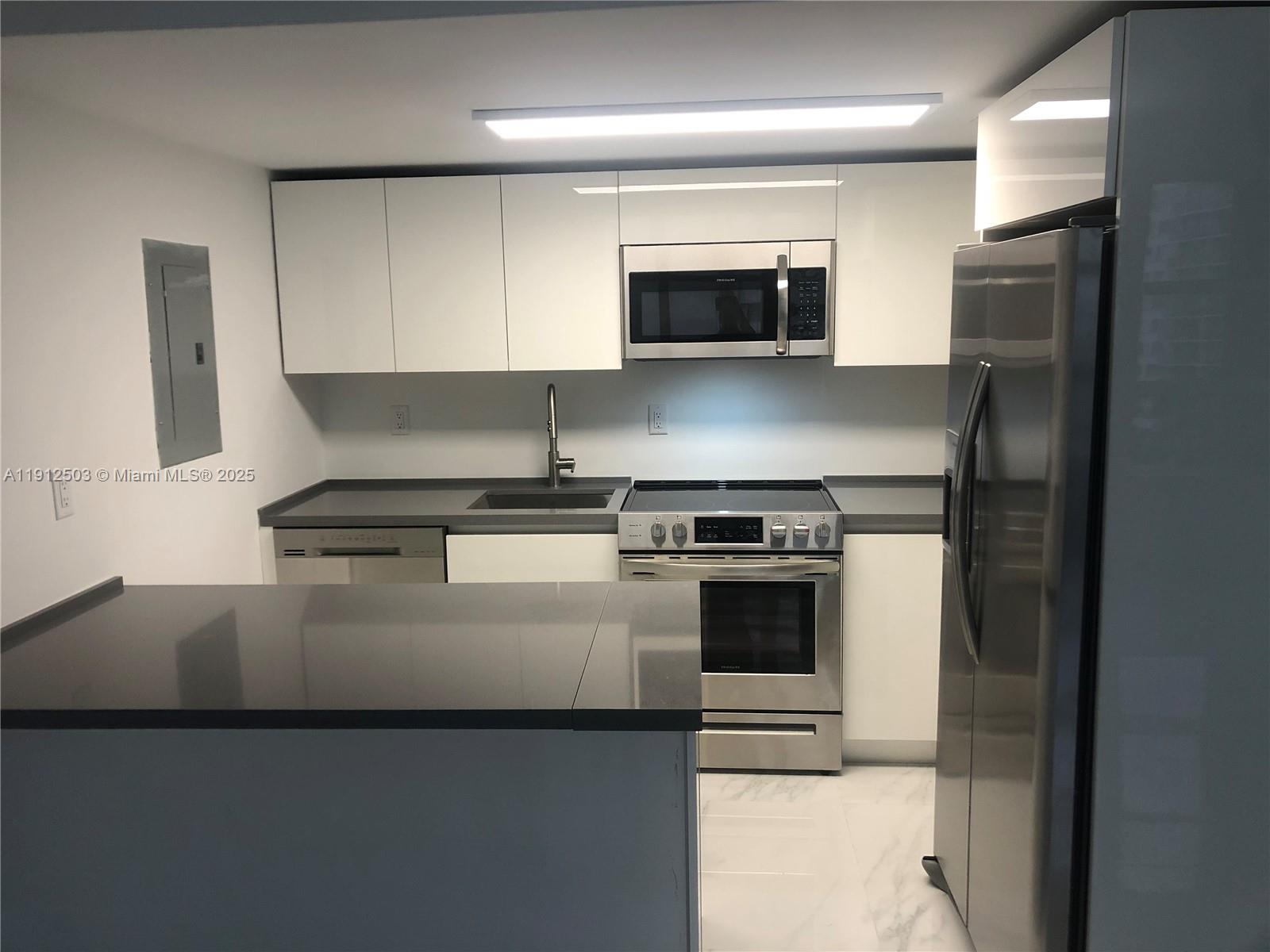 1440 Brickell Bay Drive, Unit 709 Miami, FL 33131 - Photo 2 of 13 a kitchen with a stove and a microwave