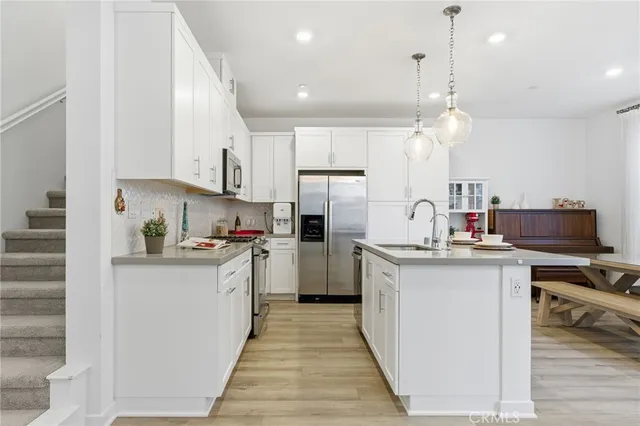 a kitchen with kitchen island a stove a refrigerator a dining table and chairs with wooden floor