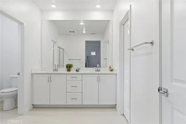 a spacious bathroom with a double vanity sink a mirror and a