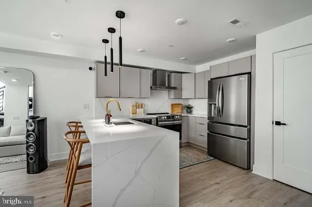 a kitchen with stainless steel appliances a refrigerator stove and wooden floor