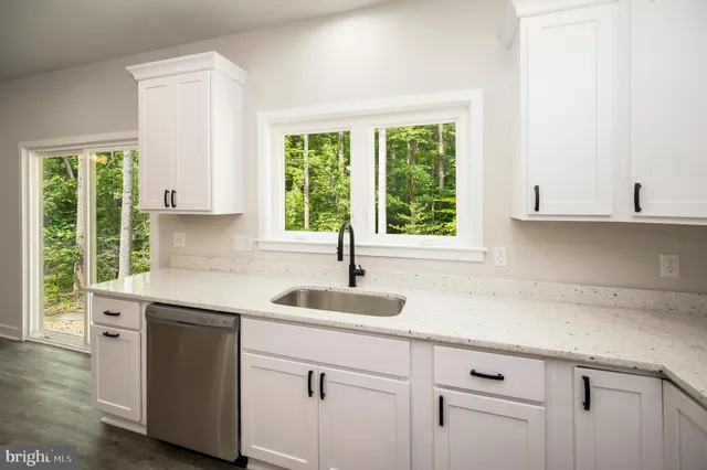 a kitchen with granite countertop a sink and white cabinets
