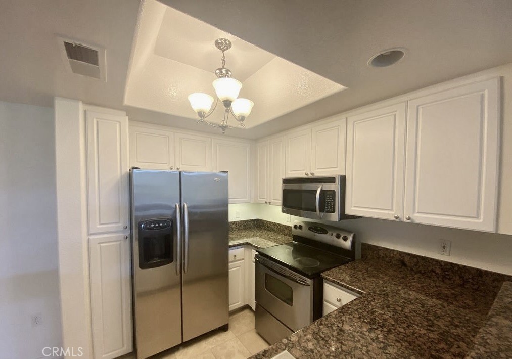 9293 Regents Road, Unit C303 La Jolla, CA 92037 - Photo 2 of 9 a kitchen with stainless steel appliances granite countertop a refrigerator a stove a microwave oven with white cabinets and granite countertops