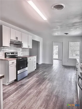 a kitchen with stainless steel appliances granite countertop a stove a sink dishwasher and a refrigerator with wooden floors