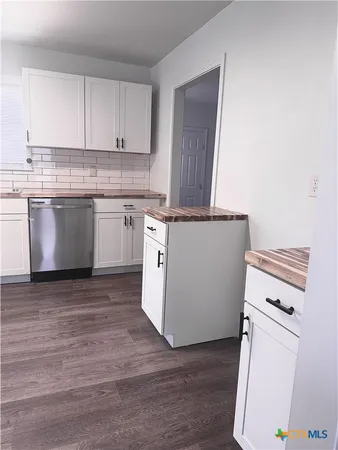 a kitchen with granite countertop a sink a stove and wooden floor