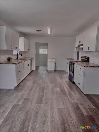 a large kitchen with cabinets wooden floor and stainless steel appliances