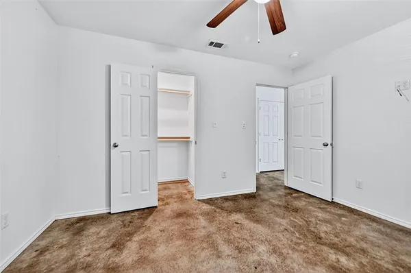 an empty room with closet fan window and closet