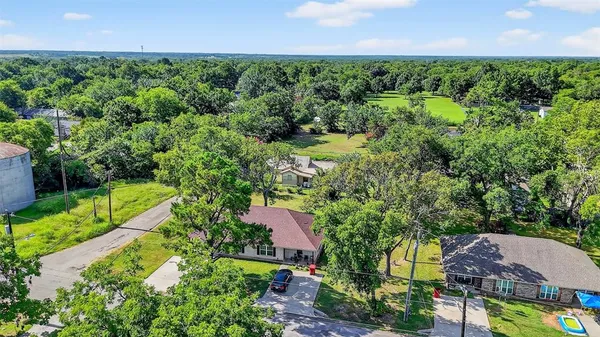 an aerial view of residential house with outdoor space and trees all around