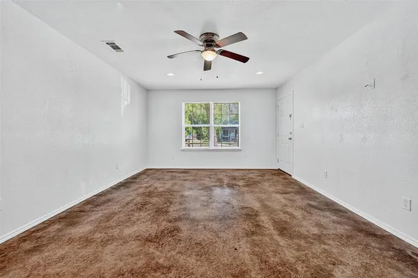 an empty room with window and ceiling fan
