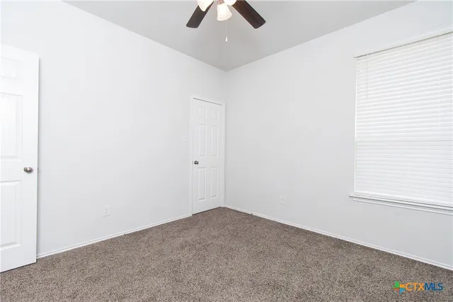 an empty room with a window and a ceiling fan