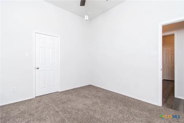 an empty room with a ceiling fan and wooden floor