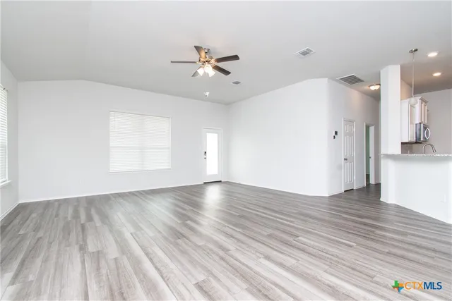 an empty room with wooden floor and windows