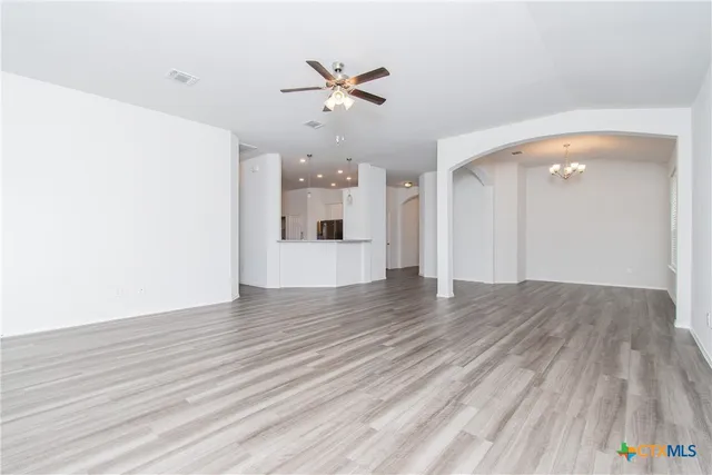 a view of empty room with wooden floor and ceiling fan