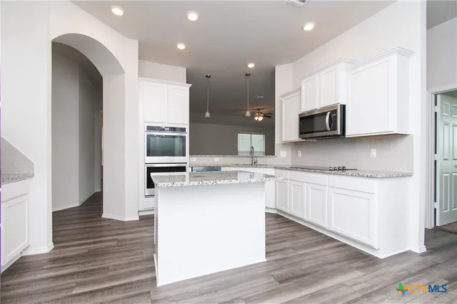 a kitchen with stainless steel appliances kitchen island granite countertop a stove a sink and a microwave