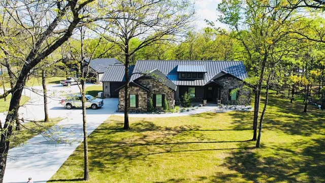 an aerial view of a residential houses with outdoor space and trees all around