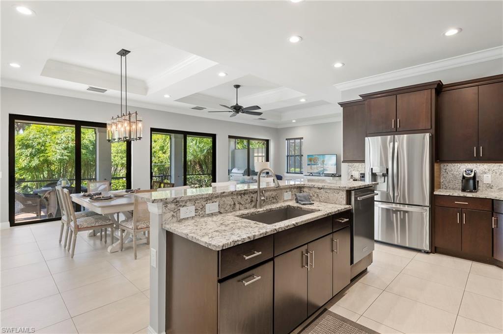 14517 Marsala Way Naples, FL 34109 - Photo 6 of 33 a kitchen with kitchen island granite countertop a table chairs stove and refrigerator