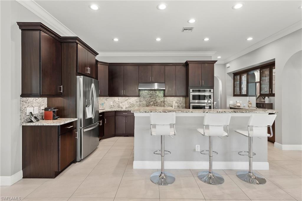 14517 Marsala Way Naples, FL 34109 - Photo 9 of 33 a kitchen with stainless steel appliances kitchen island granite countertop a refrigerator and cabinets