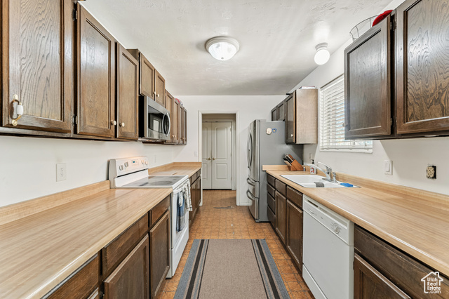 8843 Capernaum Road West Jordan, UT 84088 - Photo 7 of 31 Kitchen featuring stainless steel appliances, light countertops, and dark brown cabinetry