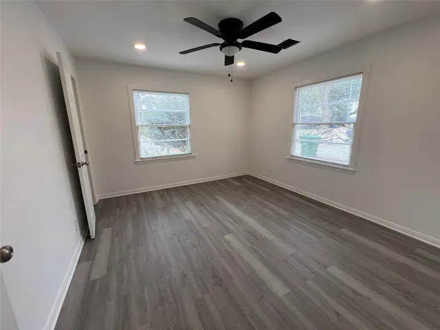 a view of an empty room with a window and wooden floor