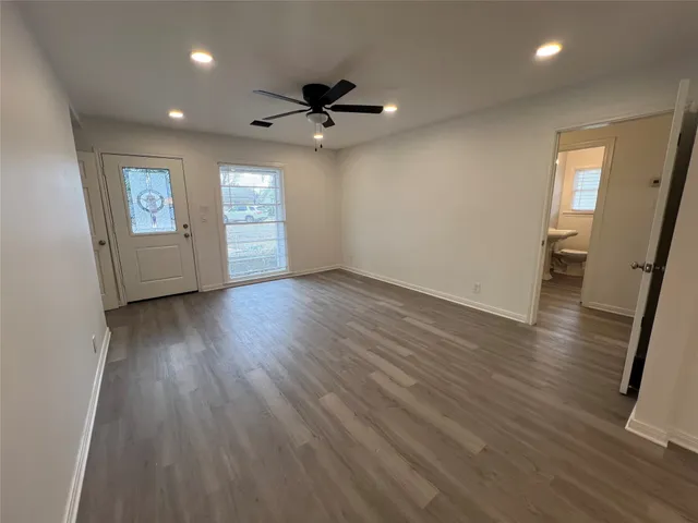 an empty room with wooden floor and windows