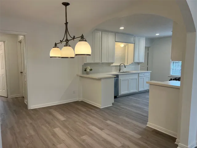 a kitchen with stainless steel appliances granite countertop a sink cabinets and wooden floor