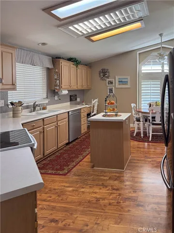 a kitchen with stainless steel appliances granite countertop a sink dishwasher stove top oven a dining table and chairs with wooden floor