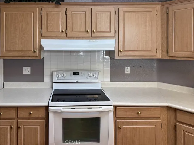 a kitchen with granite countertop white cabinets and white stove