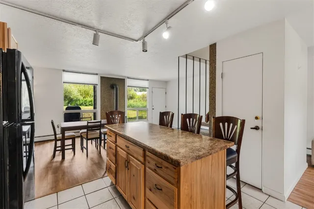 a dining hall with stainless steel appliances granite countertop a table chairs and a refrigerator