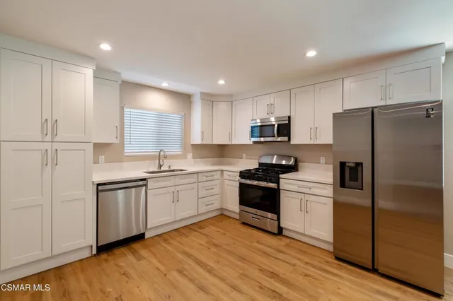 a kitchen with granite countertop a refrigerator stove top oven and sink