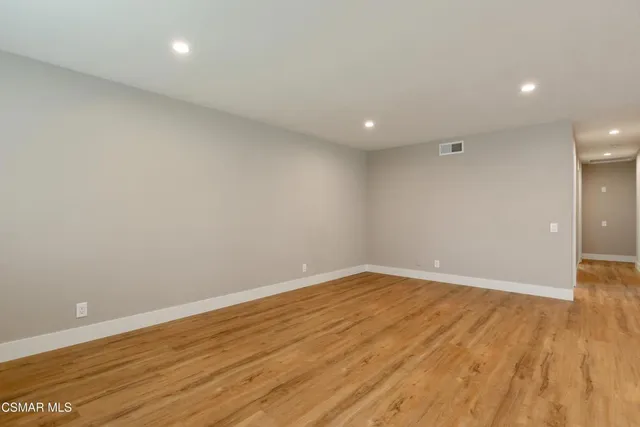 an empty room with wooden floor and natural light