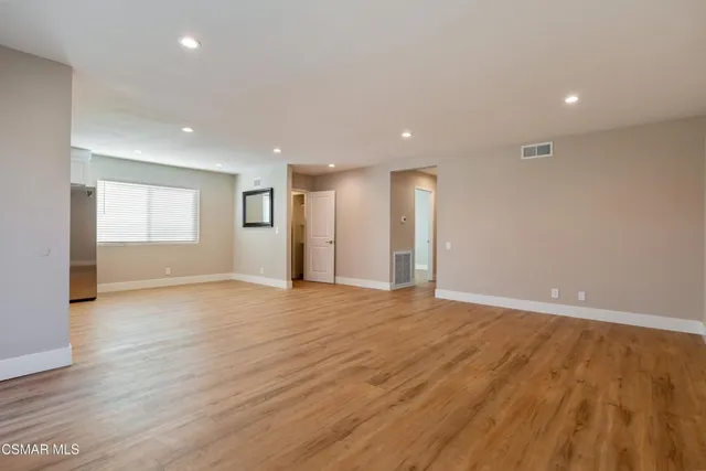 a view of an empty room with wooden floor and windows