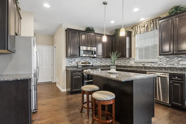 a kitchen with stainless steel appliances granite countertop a sink a stove a refrigerator and island