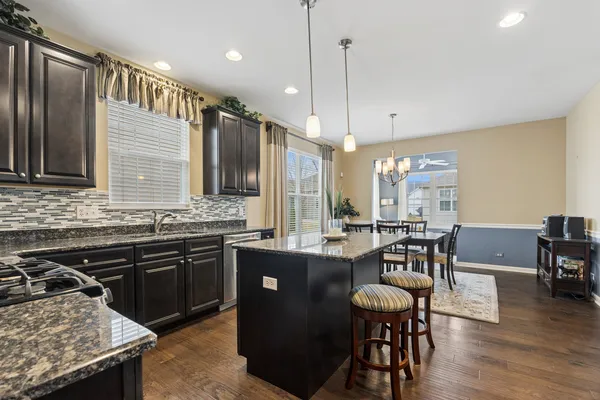 a kitchen with granite countertop a stove a sink a dining table and chairs