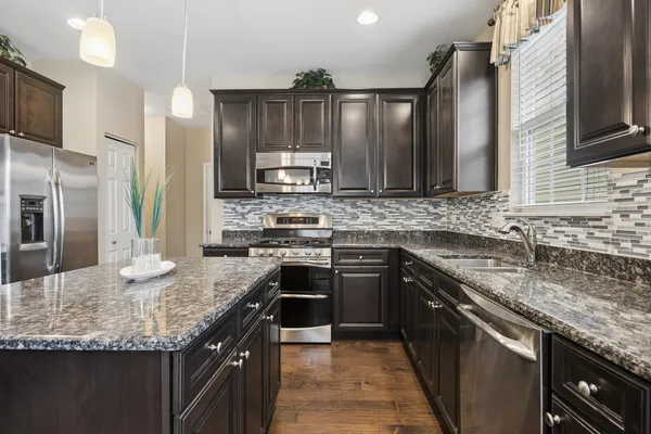 a kitchen with stainless steel appliances granite countertop a sink stove and refrigerator